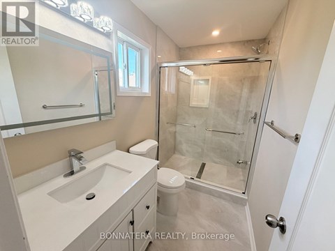A white bathroom with a glass shower stall and a sink.