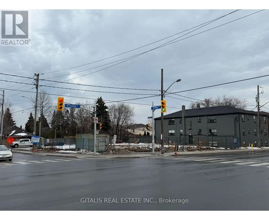 A street view with a car driving on the road and a building in the background.