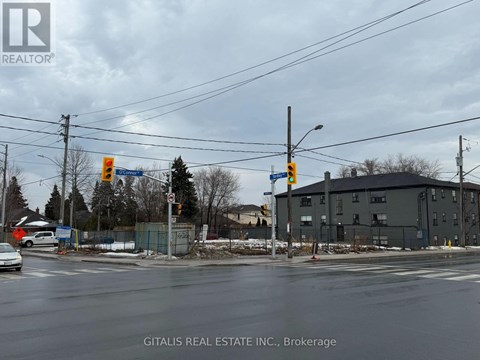 A street view with a car driving on the road and a building in the background.