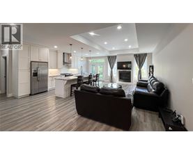A modern living room with a kitchen in the background.