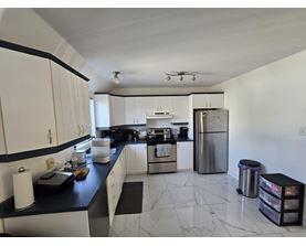 A kitchen with white cabinets and a black counter top.