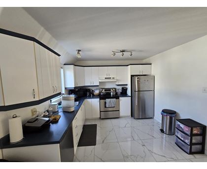 A kitchen with white cabinets and a black counter top.