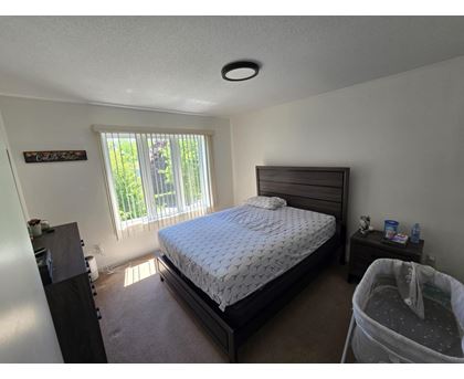 A bedroom with a bed, nightstand, and window.