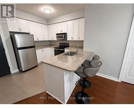 A kitchen with white cabinets and a marble island.