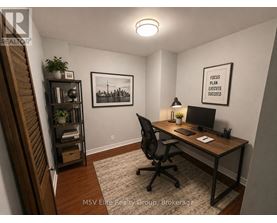 A room with a desk, chair, and a framed picture on the wall.