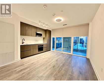 A spacious kitchen with wooden cabinets and a large window overlooking the city.