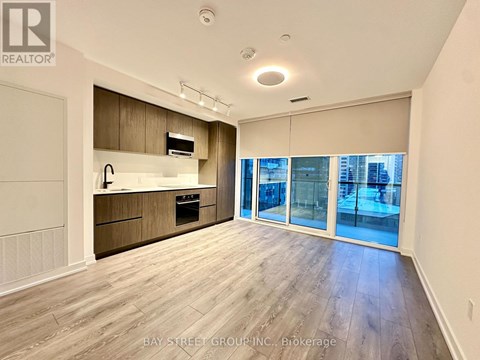 A spacious kitchen with wooden cabinets and a large window overlooking the city.
