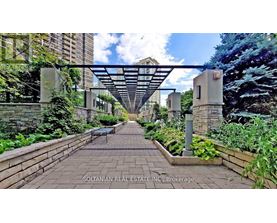 A garden pathway leads to a building with a canopy overhead.