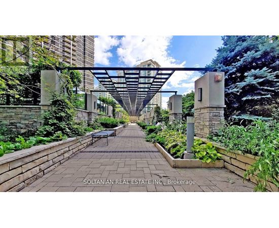A garden pathway leads to a building with a canopy overhead.