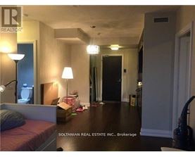 A bedroom with a bed, a lamp, and a dresser.