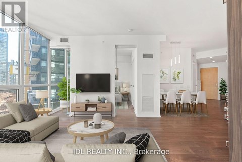 A modern living room with a flat screen TV, a sofa, a coffee table, and a dining table with chairs.