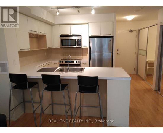 A kitchen with white cabinets and a stainless steel refrigerator.