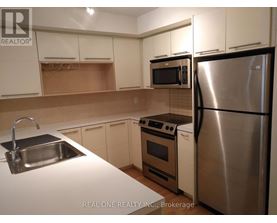 A kitchen with white cabinets and a stainless steel refrigerator.