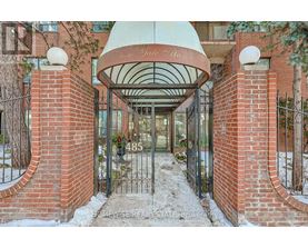 The entrance to a building with a red brick wall and a white dome above the gate.