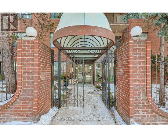 The entrance to a building with a red brick wall and a white dome above the gate.