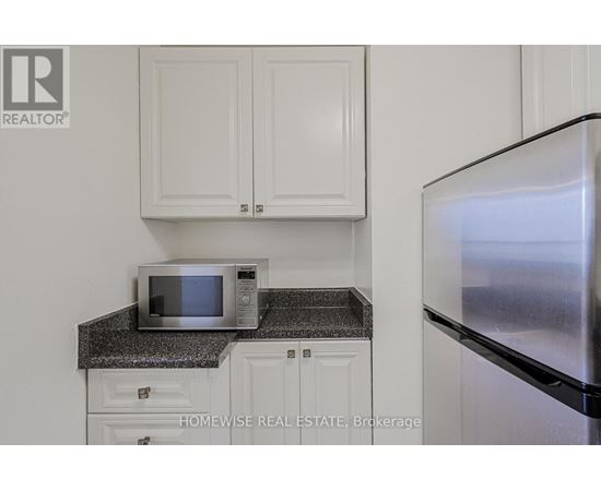 A kitchen with a microwave on a counter and a refrigerator.