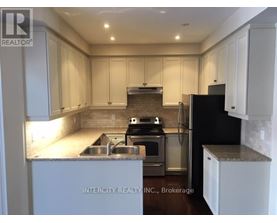 A kitchen with white cabinets and a black refrigerator.