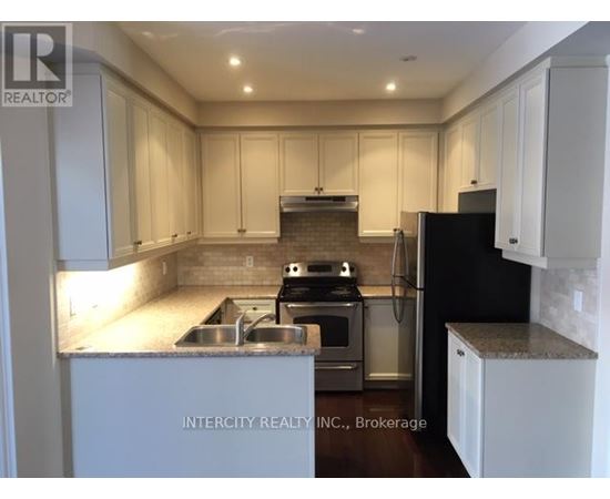 A kitchen with white cabinets and a black refrigerator.