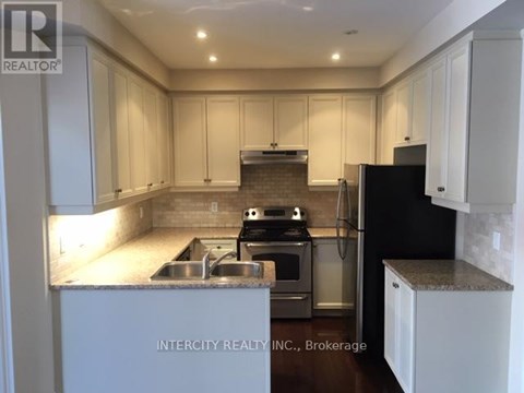 A kitchen with white cabinets and a black refrigerator.