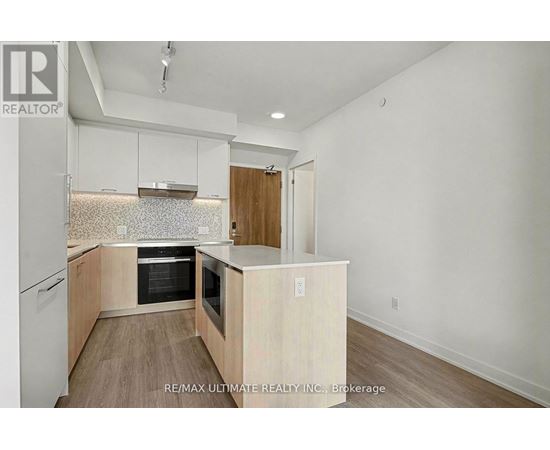 A kitchen with white cabinets and a wood floor.