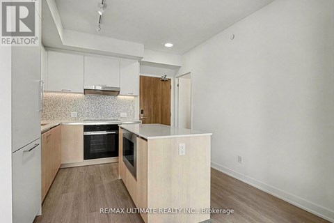 A kitchen with white cabinets and a wood floor.