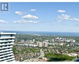 A cityscape with a tall building on the left and a view of the city and water in the distance.