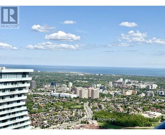 A cityscape with a tall building on the left and a view of the city and water in the distance.
