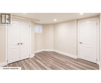 A bedroom with a white door and a white wall.