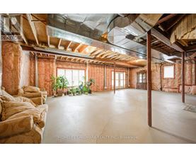 A spacious room with exposed wooden beams and a concrete floor.