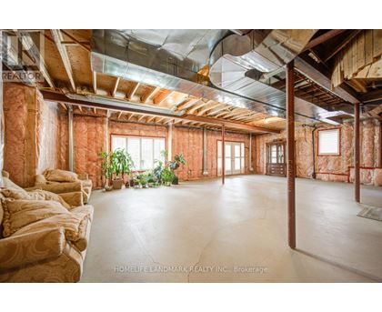 A spacious room with exposed wooden beams and a concrete floor.
