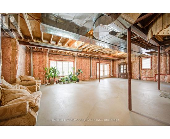 A spacious room with exposed wooden beams and a concrete floor.