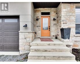 A house with a brown garage door and a red mat on the steps.