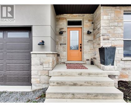 A house with a brown garage door and a red mat on the steps.