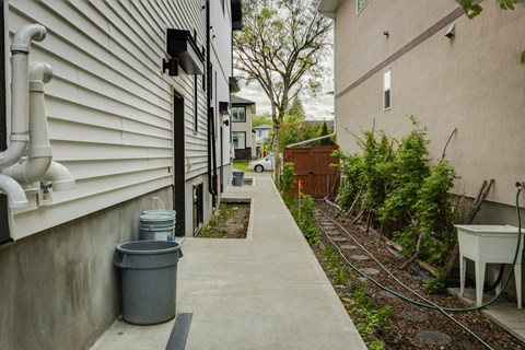 A concrete walkway leads to a small garden area.