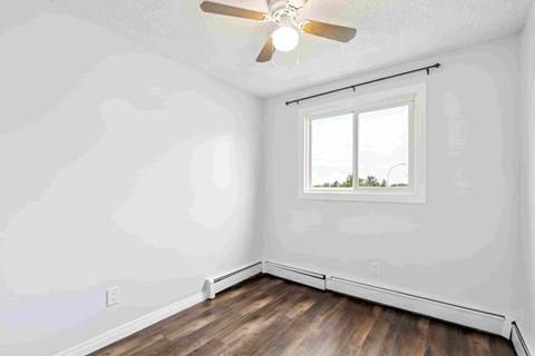 A room with a ceiling fan and a window showing a view of trees.