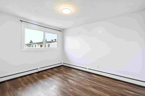 A room with a window and wooden flooring.