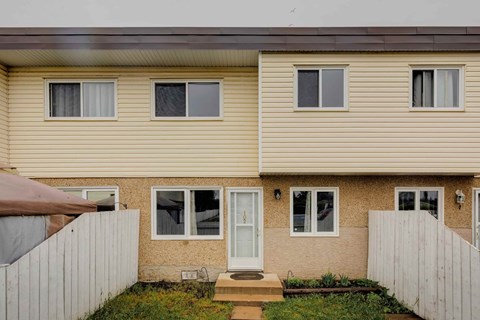 A beige house with a white door and windows.