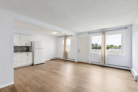A spacious room with wooden flooring and white walls.