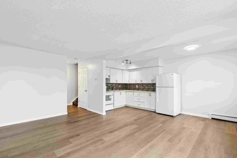 A kitchen with white cabinets and a wooden floor.