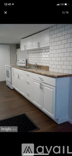 A kitchen with white cabinets and a brick wall backsplash.