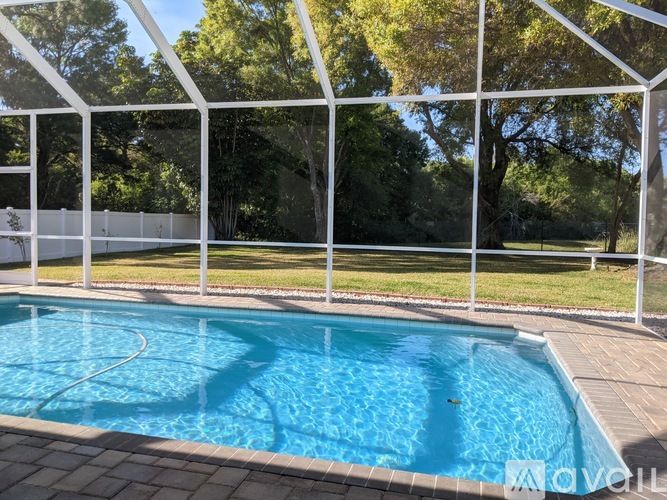A pool enclosed by a white fence and a glass wall.