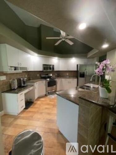 A kitchen with a brown counter top and a ceiling fan.