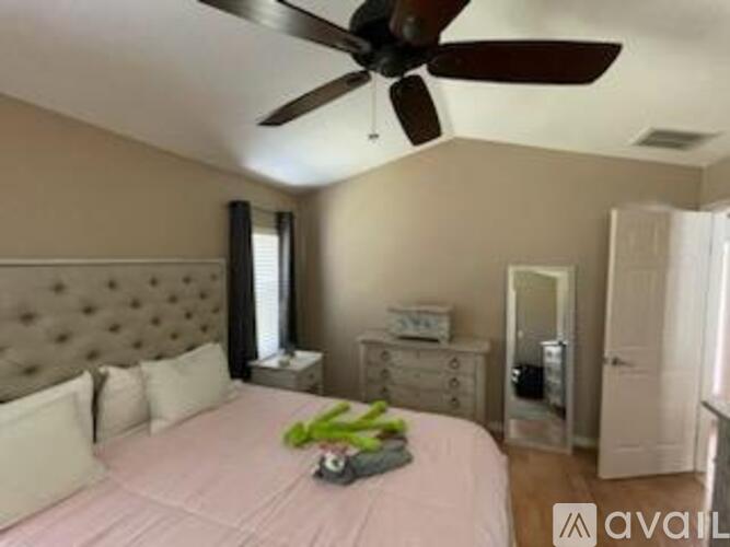 A bedroom with a bed, dresser, and ceiling fan.