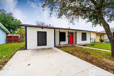 A small white house with a red door is for sale.