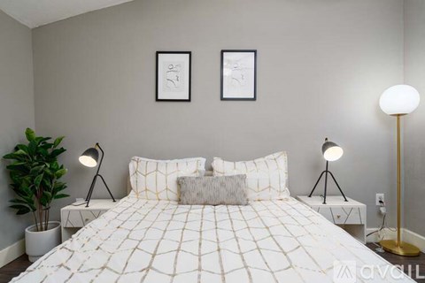 A bedroom with a large bed and two lamps.