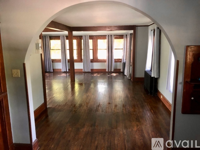 A spacious room with wooden floors and a large arched opening.