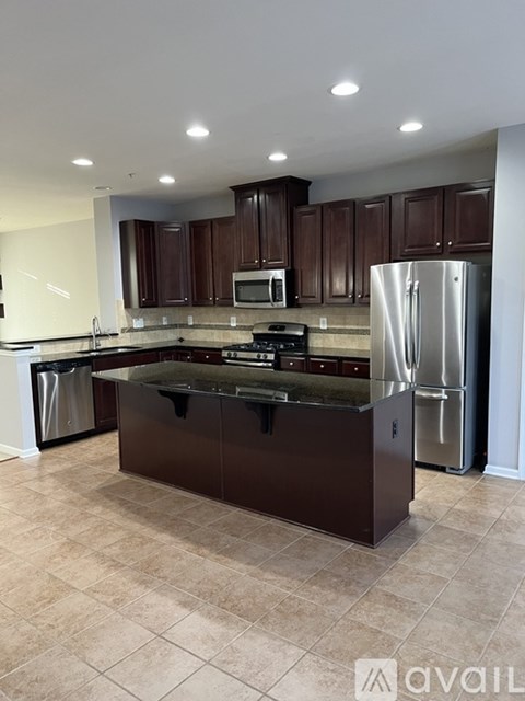 A kitchen with brown cabinets and a black island.
