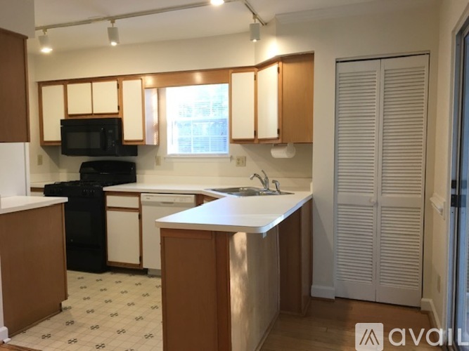 A kitchen with wooden cabinets and a black microwave.