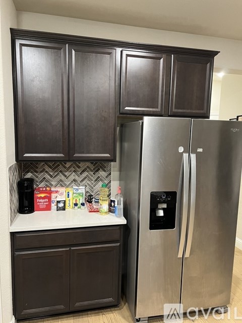 A kitchen with a stainless steel refrigerator and dark brown cabinets.
