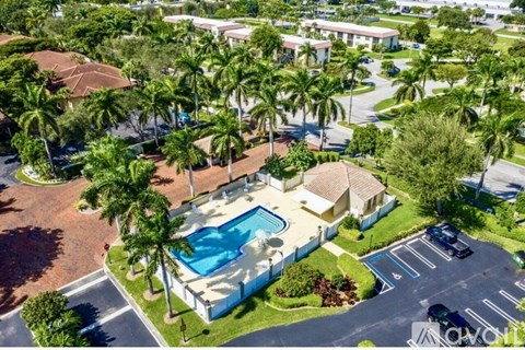 A bird's eye view of a residential area with a swimming pool surrounded by palm trees.